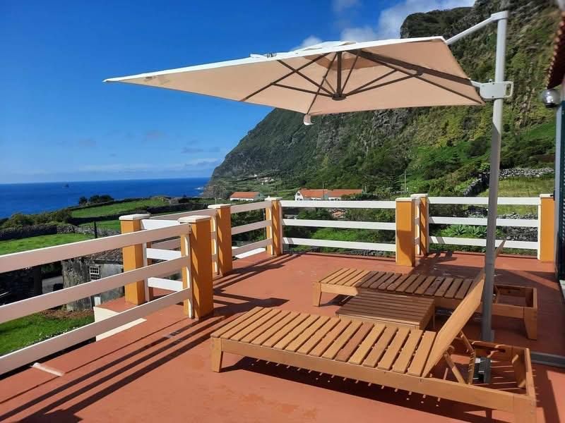 The sun terrace with loungers and a parasol above the cliffs