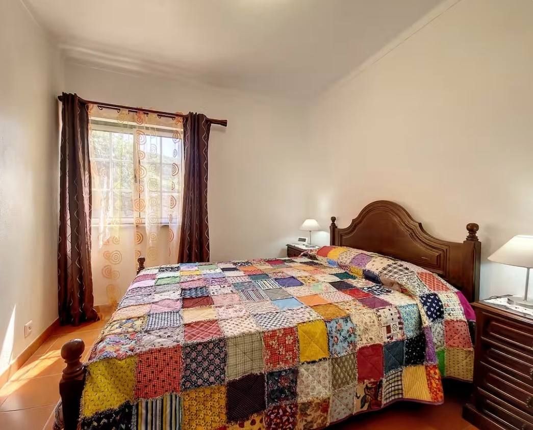 Bedroom 3, queen bed with a patchwork quilt and the window onto the garden