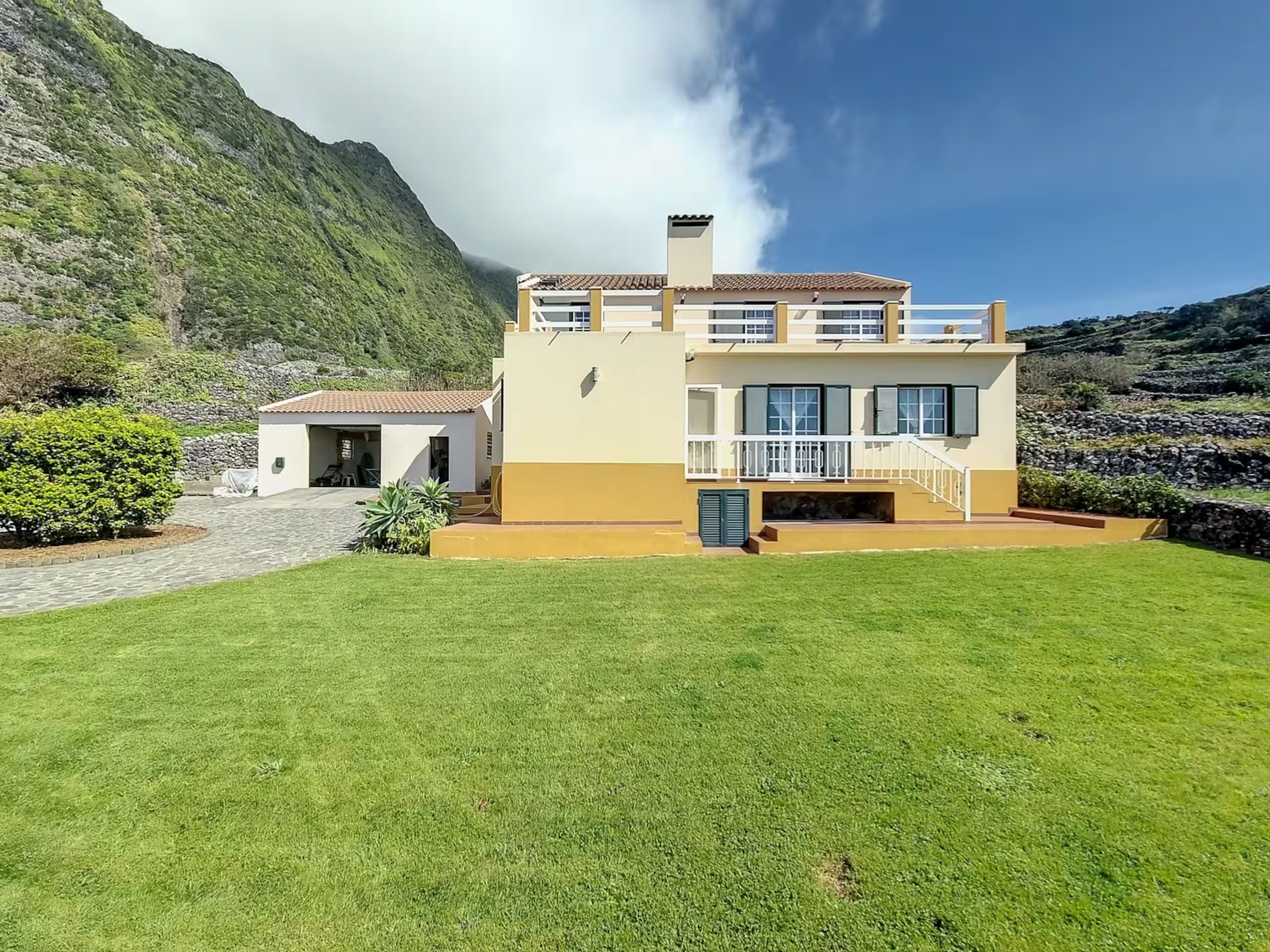 The lawn in front of the house, with the cliffs rising behind it